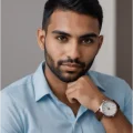 Retrato de homem moreno com camisa azul e relógio. Estilo casual e moderno.